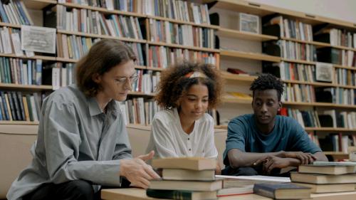 Drie mensen en een berg met boeken