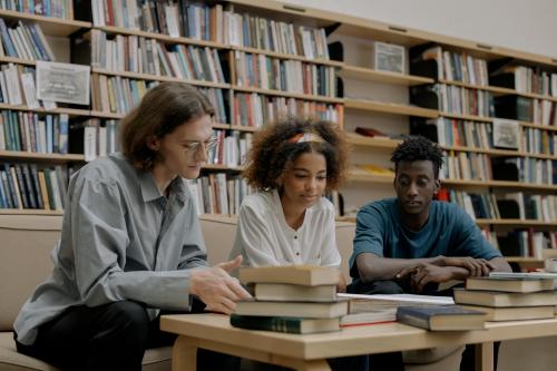Drie mensen en een berg met boeken