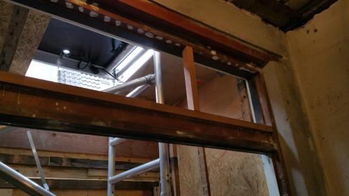 De zelfgemaakte houten bovenpartij in aanbouw, met het kalf en de verticale verdeling voor de bovenlichten nog zonder glas.
