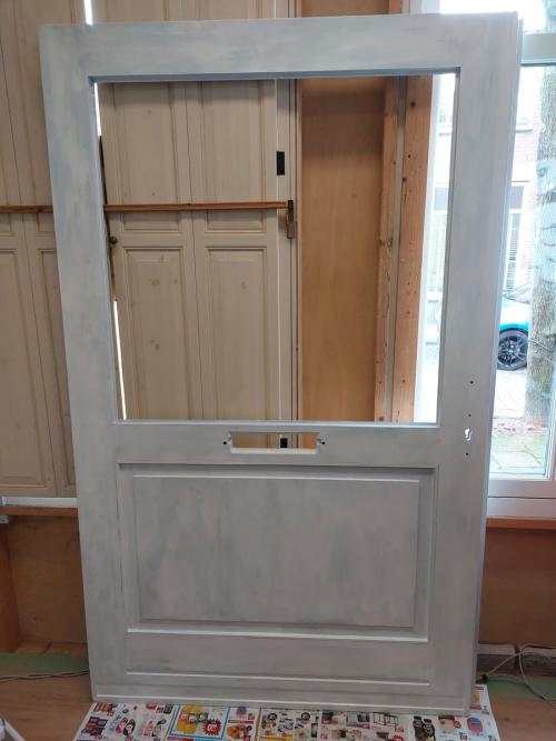 De herstelde deur in de grondverf, met de openingen voor glas en beslag nog zichtbaar.