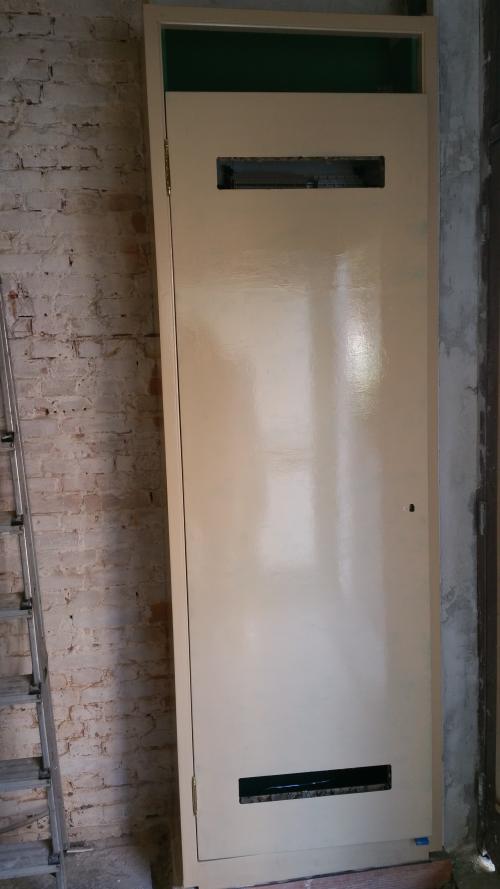 The painted cupboard door with two openings, before the ventilation grilles were fitted.